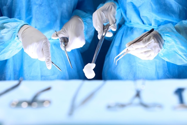 Медицинская бригада, выполняющая операцию. Группа хирургов работает в операционной, окрашенной в синий цвет.