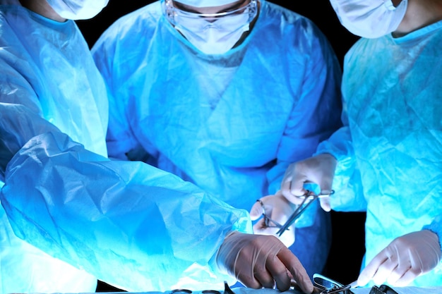 Medical team performing operation Group of surgeon at work in operating theatre toned in blue