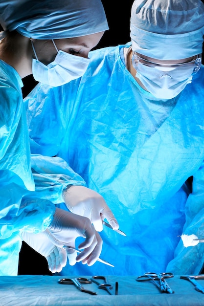 Foto equipe medica che esegue l'operazione. gruppo di chirurgo al lavoro in sala operatoria nei toni del blu.