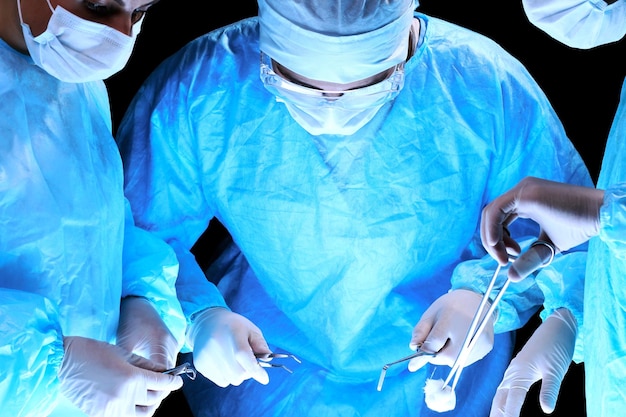 Medical team performing operation. Group of surgeon at work in operating theatre toned in blue.