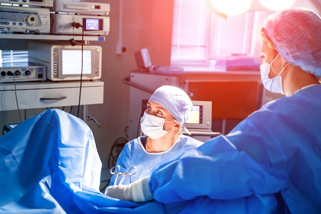 Медицинская бригада проводит хирургическую операцию в яркой современной операционной Операционная Современное оборудование в клинике Скорая помощь