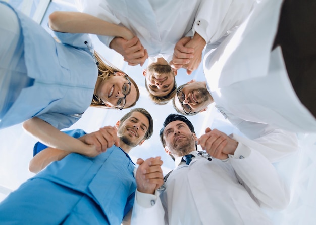 Foto equipe medica in piedi raggruppata in cerchio che guarda la telecamera