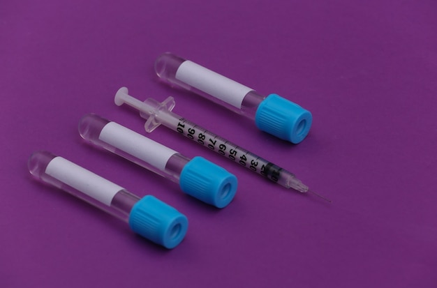 Medical test tubes with syringes on purple background.