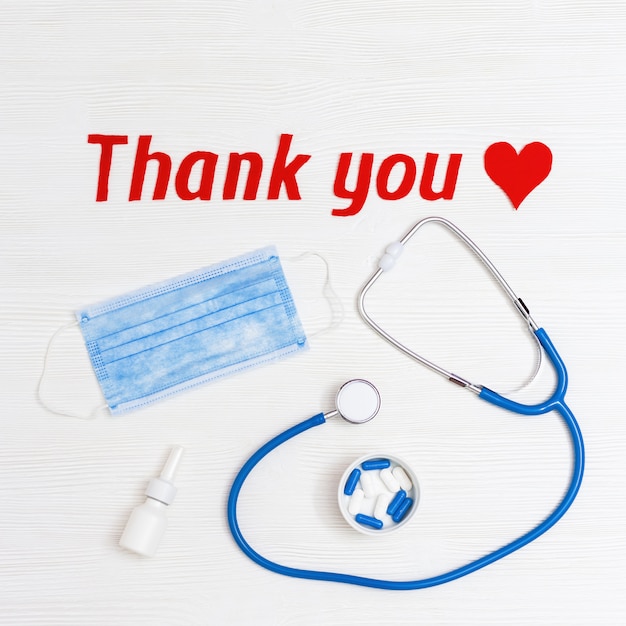 Medical things on table red heart and text "thank you" on white wood