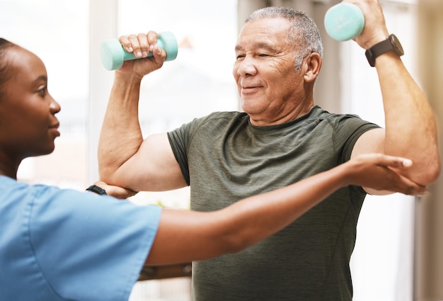 Medical training and physiotherapy with dumbbell and old man with nurse for rehabilitation support and retirement Healthcare help and physical therapy with patient and black woman in nursing home