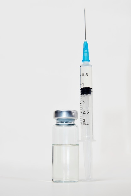 Medical vaccination concept with syringe and medical ampoules. Vaccine bottle and syringe injection on white background with copy space, close-up