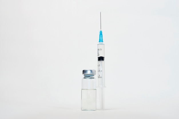 Medical vaccination concept with syringe and medical ampoules. Vaccine bottle and syringe injection on white background with copy space, close-up