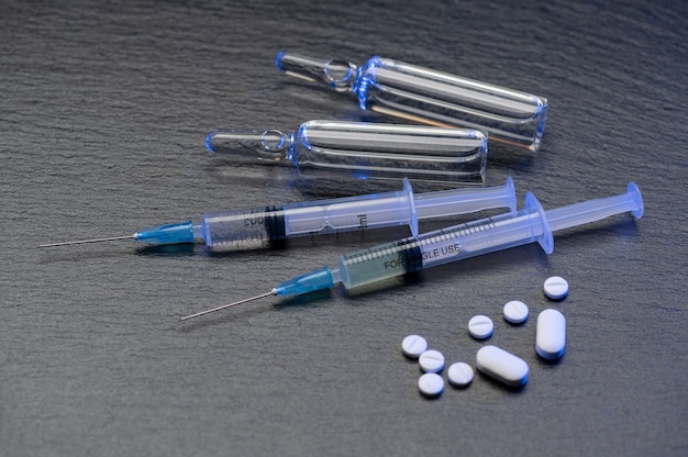 Medical vial and ampoules for injection and syringe and pills on the grey glossy table