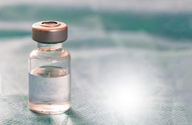 灰色の背景の透明なガラス瓶の薬薬ワクチン用量の注射用医療バイアル