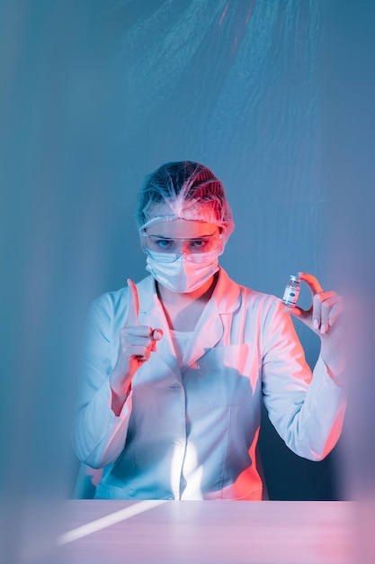 Medical warning Mandatory vaccination Forced coronavirus immunization Female doctor in ppe protective face mask showing vial dose pointing up finger on blue pink background