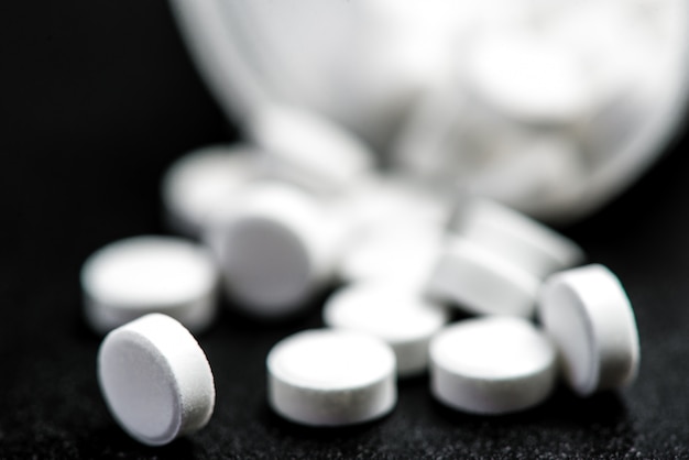 Медицинские белые таблетки для лечения и здравоохранения на черном фоне.