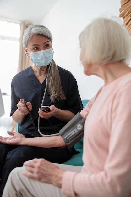 Medical worker examining elderly female at home