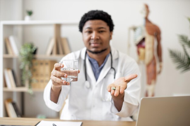 Medical worker holding water and pill on office background