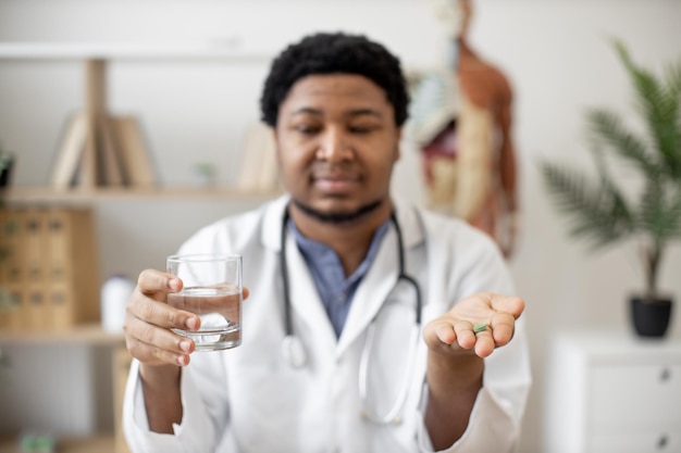 Medical worker holding water and pill on office background