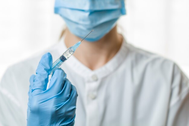 The medical worker holds a syringe with medicine in his hand