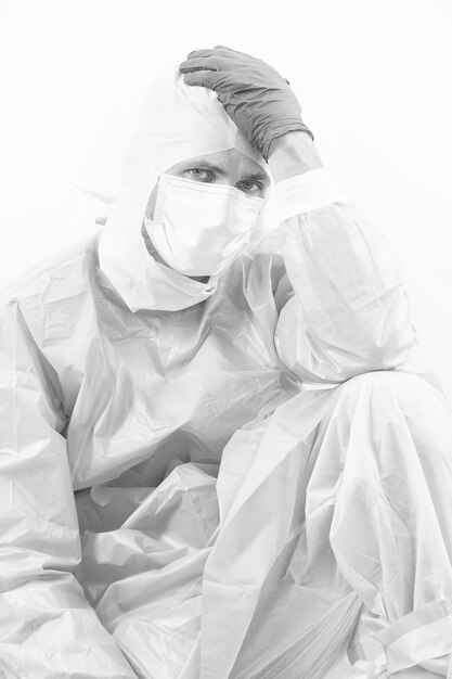 Medical worker man in protective costume isolated on white having covid19 sars virus symptoms of headache coronavirus pandemic