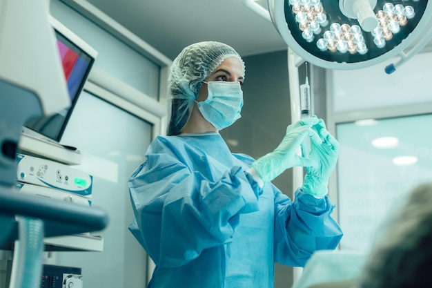 Medical worker in the operating room trying to use syringe and looking serious