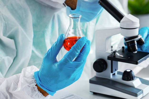 Medical worker in protective gown looking in microscope