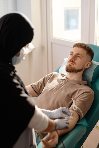 Medical Worker Removing Catheter from Arm of Male Donor