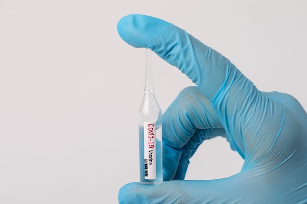 Covid-19 백신과 함께 작은 귀중한 용액을 가진 의료 노동자. 위험한 바이러스에 대한 치료법 개발