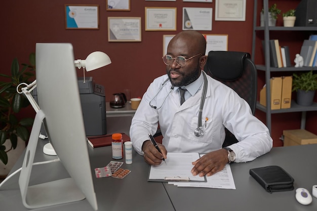 Medical Worker Writing Prescription for His Patient During Online Appointment