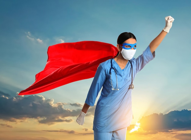 Medical workers fighting with dangerous diseases Doctor dressed as superhero posing against sky