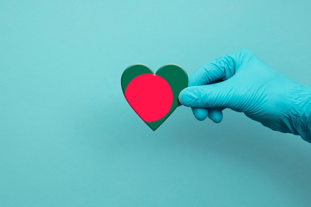 Medical workers hand wearing surgical glove holding bangladesh flag heart