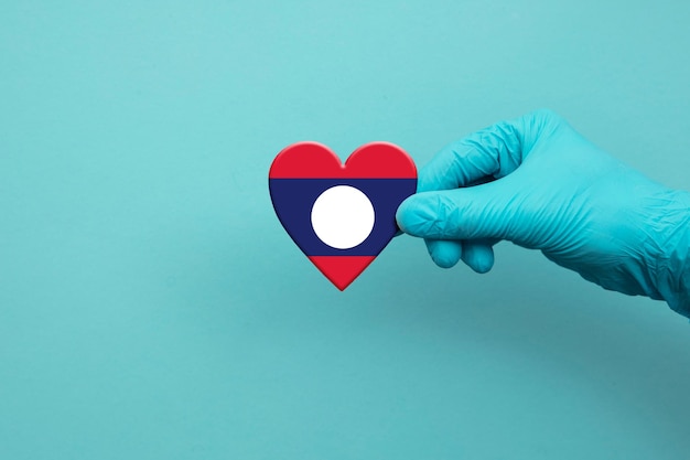 Medical workers hand wearing surgical glove holding laos flag heart