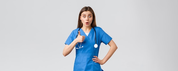 Medical workers healthcare covid19 and vaccination concept Amused and excited female nurse doctor heard about amazing news show thumbsup in approval gasping astonished