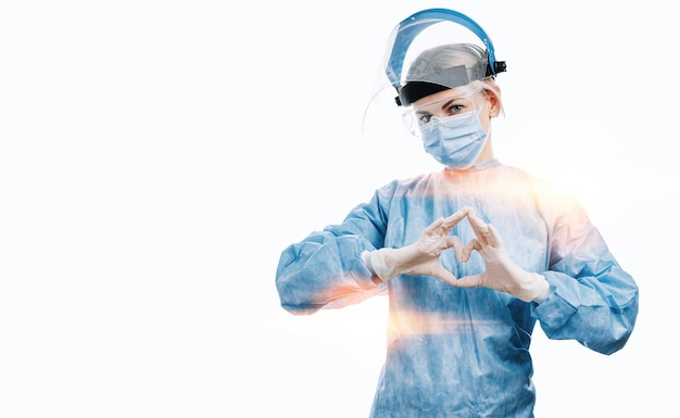 Medical workers heroes a nurse in a mask and uniform holds\
hands in the shape of a heart nurses day celebration concept