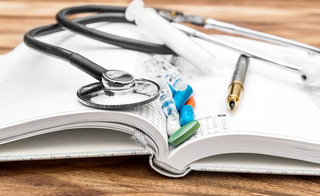 Фото Лекарства со стетоскопом и ручкой в открытом блокноте