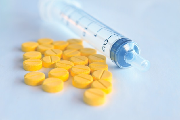 Medicatie in tabletten en insulinespuit in grijze toon onscherpe achtergrond