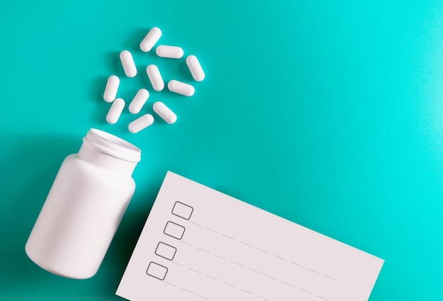 Photo medication bottle and white pills spilled on red pastel colored background.