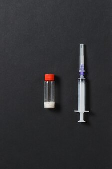 Flacone di farmaci con pillole, ago della siringa vuoto su sfondo nero