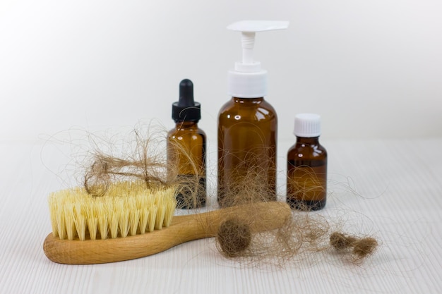 Medication bottles and hairbrush on white wooden table Hair loss problem