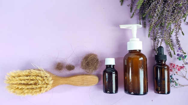 Medication bottles hairbrush with lost hair and herb heather on purple background Hair loss problem