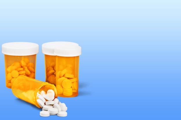 Medication pills in pills bottles on background