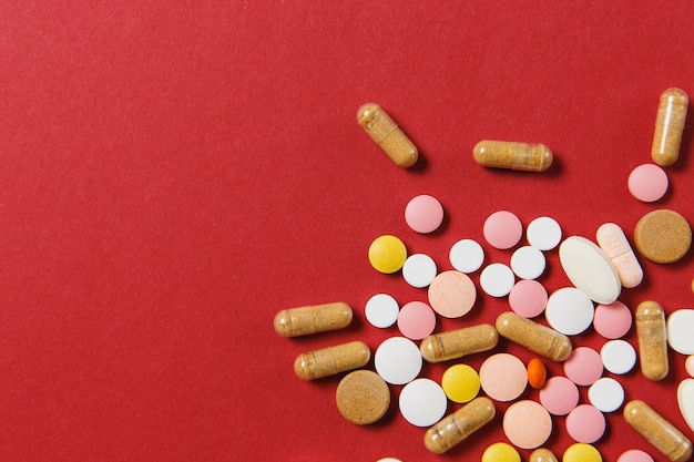 Medication white colorful round tablets arranged abstract on red color background