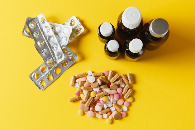 黄色の背景に抽象的な配置された薬の白いカラフルな丸い錠剤。デザイン用のボトルバイアルパッキングピル。健康治療の選択健康的なライフスタイルの概念。宇宙広告をコピーします。