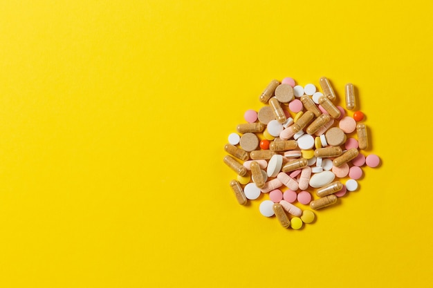 Medication white colorful round tablets arranged abstract on yellow color background