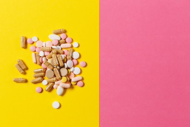 Medication white colorful round tablets arranged abstract on yellow pink color background