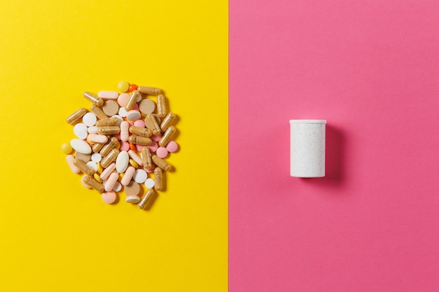 Foto compresse rotonde colorate bianche di farmaci disposte in astratto su sfondo di colore rosa giallo