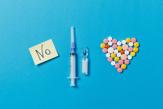 Medication white, colorful round tablets in form of heart isolated on blue background