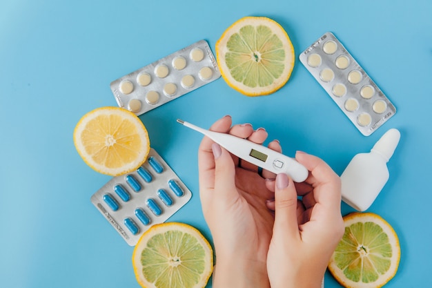 Medications, pills, thermometer, traditional medicine for treating colds, flu, heat on a blue background. Maintenance of immunity. Seasonal diseases. Top view. Medicine flat lay