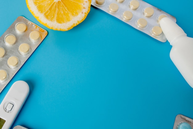 Medications, pills, thermometer, traditional medicine for treating colds, flu, heat on a blue background. Maintenance of immunity. Seasonal diseases. Top view. Medicine flat lay