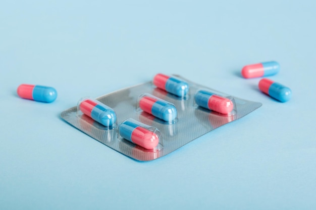 Medicijnpillen op een lichte achtergrond Geneesmiddelen en voorgeschreven pillen liggen plat op de achtergrond Blauwe en roze medische tabletten in blister