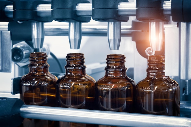 Medicijnpillen uit de farmaceutische industrie vullen de glazen fles op de transportband van de productielijn in de selectieve focus van de medische fabriek