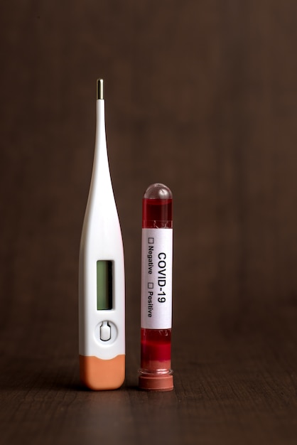 Medicijntablet en thermometer met reageerbuis met een bloedmonster om te testen op de aanwezigheid van coronavirus / covid-19
