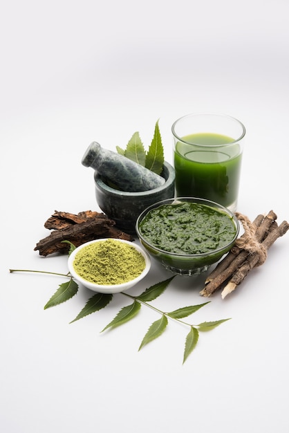 Medicinal Ayurvedic Azadirachta indica or Neem leaves in mortar and pestle with neem paste, juice and twigs, powder and oil, selective focus