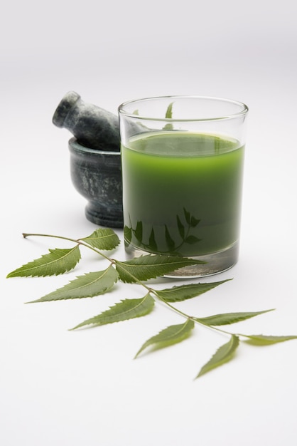 Medicinal ayurvedic azadirachta indica or neem leaves in mortar\
and pestle with neem paste, juice and twigs, powder and oil,\
selective focus